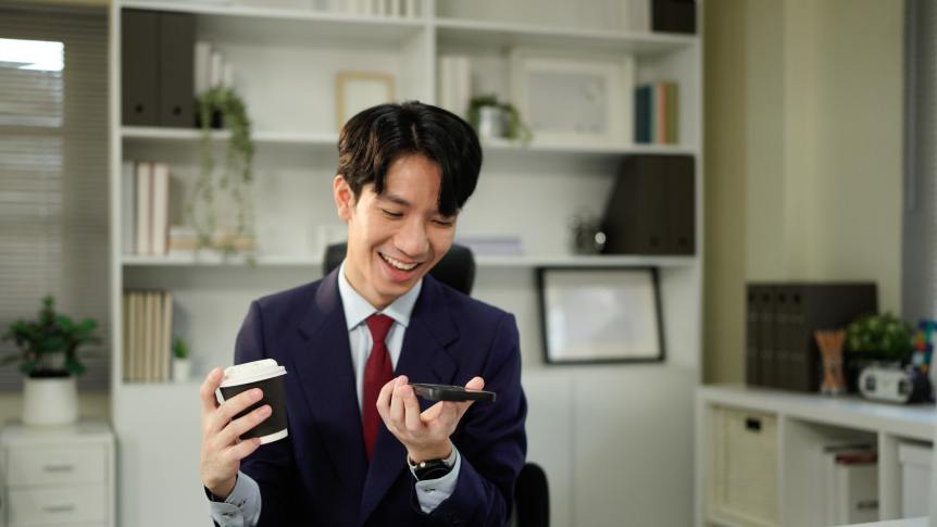 A diverse team of three professionals collaborating over a laptop in a bright, modern office.